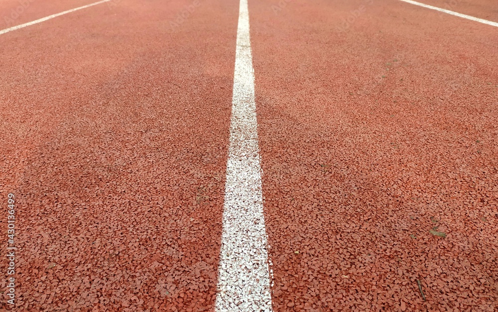 The brown surface of the stadium. The white stripe goes off into the distance The brown surface of the stadium. The white stripe goes off into the distance