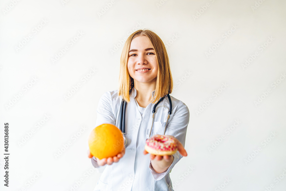 Nutritionist female doctor holding orange and donut in hands, diet concept. Nutritionist female doctor holding orange and donut in hands, diet concept.