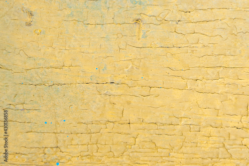Texture. Pale yellow, aged, cracked paint on a wooden surface.