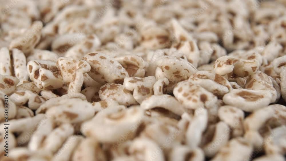 Falling flakes of puffed wheat spelt in slow motion, close-up. Detailed shot. Grained cereals. Macro Falling flakes of puffed wheat spelt in slow motion, close-up. Detailed shot. Grained cereals. Macro
