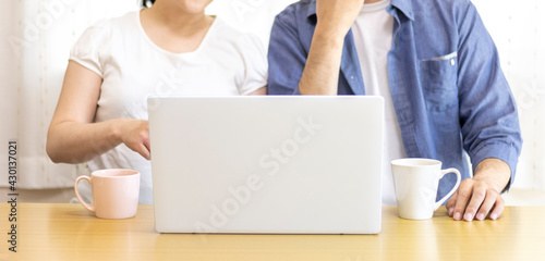 自宅でノートパソコンを使う夫婦のイメージ（日本人、30代）