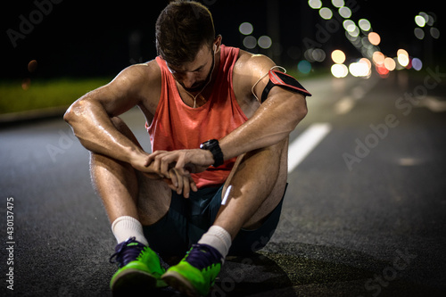 Male runner resting after night workout in the city.