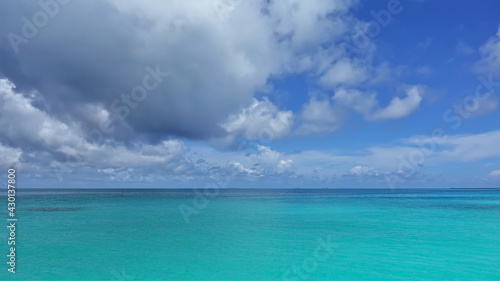 Calm waters of the aquamarine Indian Ocean. There are picturesque cumulus clouds in the azure sky. Nobody. Maldivian idyll.