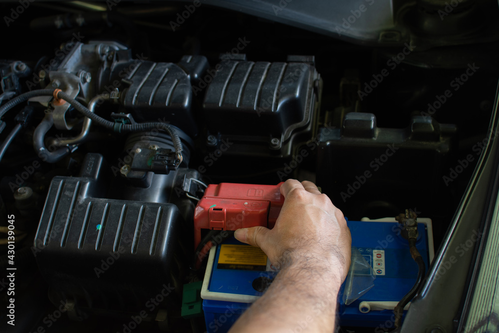 Concept of engine maintenance. Technician is checking the level of power battery. Hand of men are examining their cars' main power sources and electrical systems. DC power failed. Blurred background