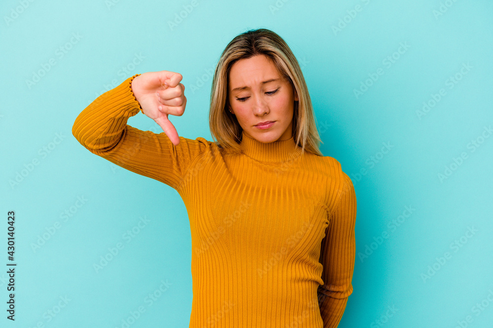 Young mixed race woman isolated on blue background showing a dislike gesture, thumbs down. Disagreement concept. Young mixed race woman isolated on blue background showing a dislike gesture, thumbs down. Disagreement concept.