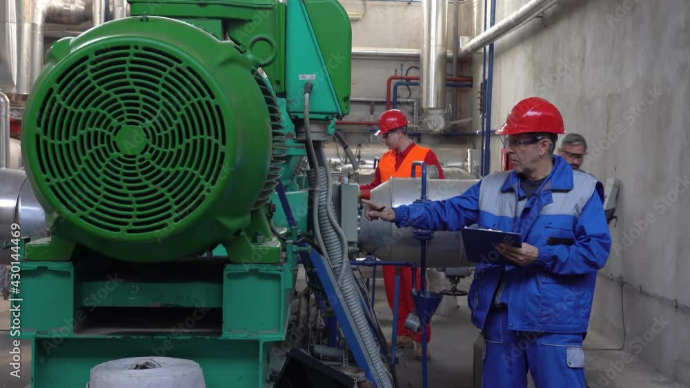 Machine Operator Writing on Clipboard and Talking to Maintenance Engineer with Digital Tablet Machine Operator Writing on Clipboard and Talking to Maintenance Engineer with Digital Tablet
