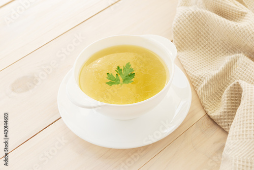 Chicken broth with parsley in a white bowl.