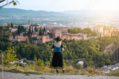 A young female traveler with sunglasses and casual style contemplates the views of the Alhambra palace in the city of Granada, Spain