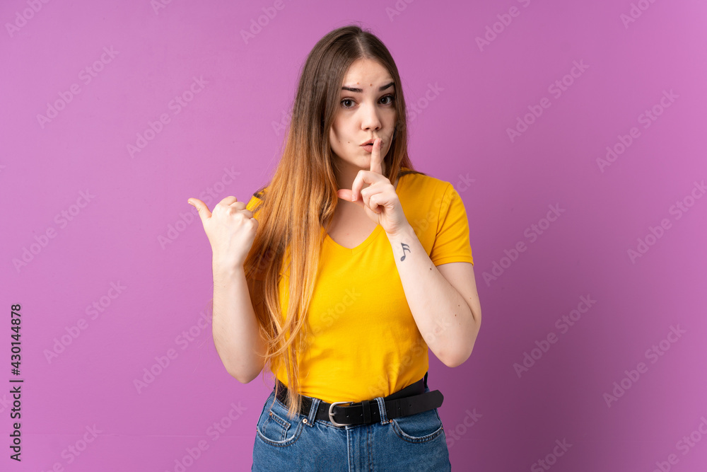 Young caucasian woman isolated on purple background pointing to the side and doing silence gesture Young caucasian woman isolated on purple background pointing to the side and doing silence gesture