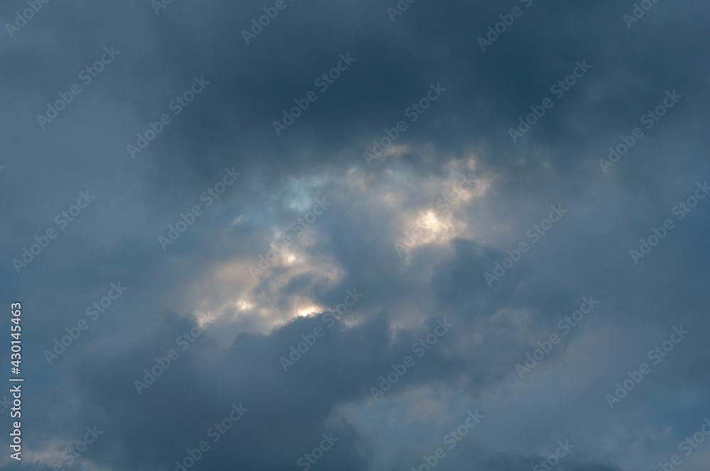 Covered with dark blue clouds with small gap through which sun's rays and bright blue sky break through. Covered with dark blue clouds with small gap through which sun's rays and bright blue sky break through.
