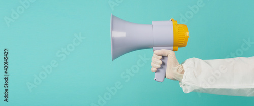 Hand is hold megaphone and wear PPE suit on green mint color or Tiffany Blue background..