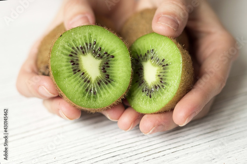 Female hands hold ripe kiwi