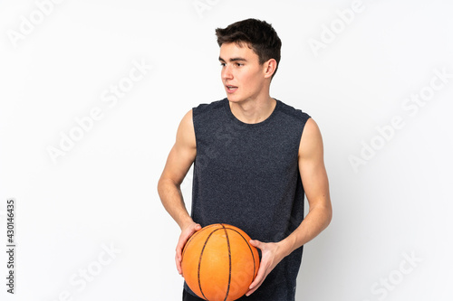 Handsome young basketball player man over isolated wall playing basketball