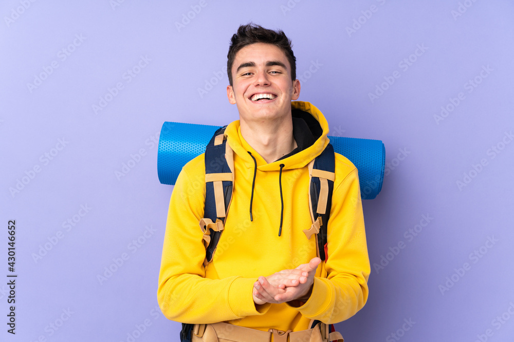 Teenager caucasian mountaineer man with a big backpack isolated on purple background applauding Teenager caucasian mountaineer man with a big backpack isolated on purple background applauding