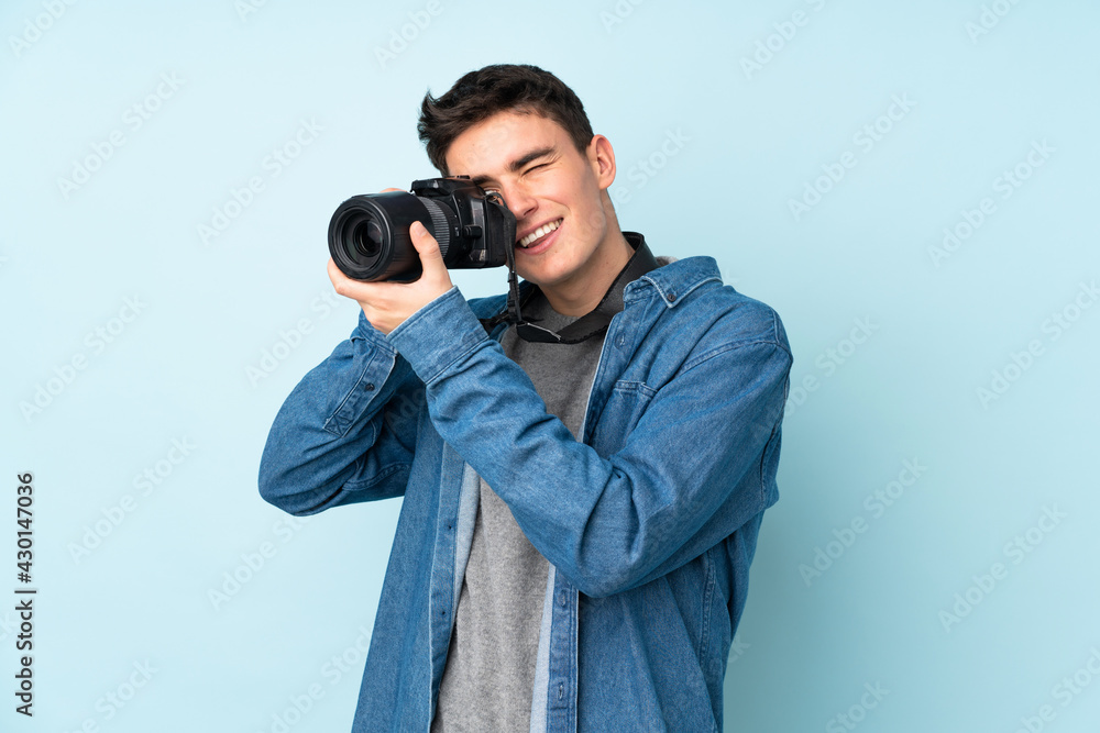 Teenager photographer man isolated on blue background Teenager photographer man isolated on blue background