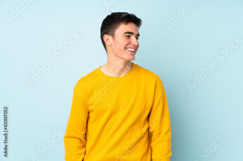 Teenager caucasian handsome man isolated on purple background looking side