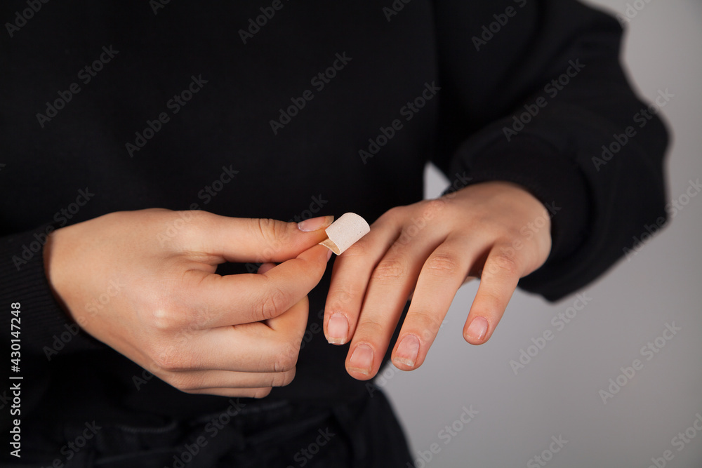 Caucasian woman putting adhesive bandage on her finger.