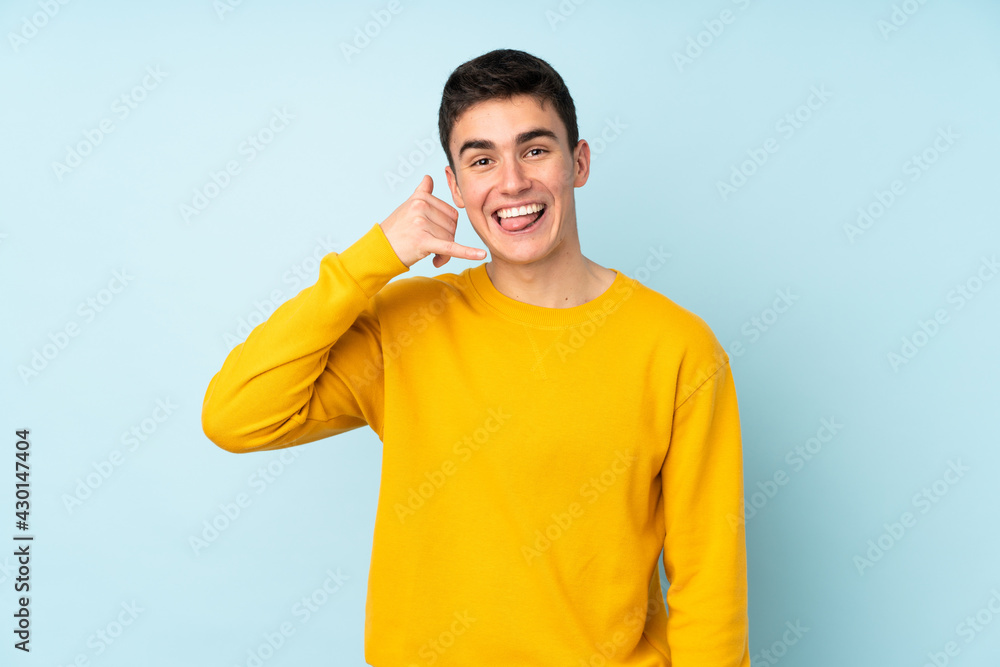Teenager caucasian handsome man isolated on purple background making phone gesture. Call me back sign Teenager caucasian handsome man isolated on purple background making phone gesture. Call me back sign