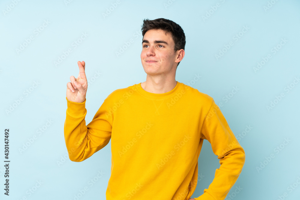 Teenager caucasian handsome man isolated on purple background with fingers crossing and wishing the best Teenager caucasian handsome man isolated on purple background with fingers crossing and wishing the best