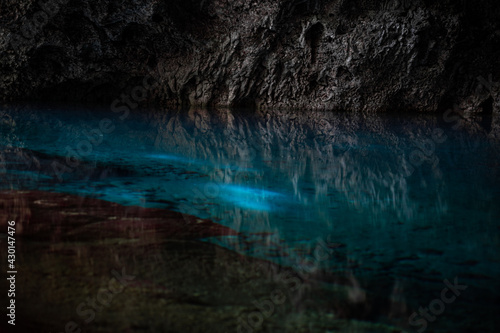 Light descends into the darkness of a submerged cavern with blue lake. Concept of travel and adventure.
