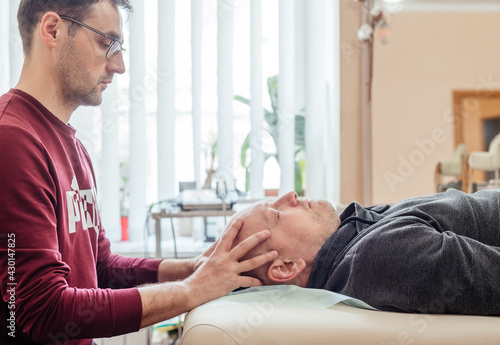 Male patient receiving cranial sacral therapy, lying on the massage table in CST osteopathic clinic, osteopathy and manual therapy