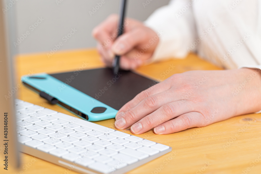 A graphic designer works on a digital tablet. work from home A graphic designer works on a digital tablet. work from home