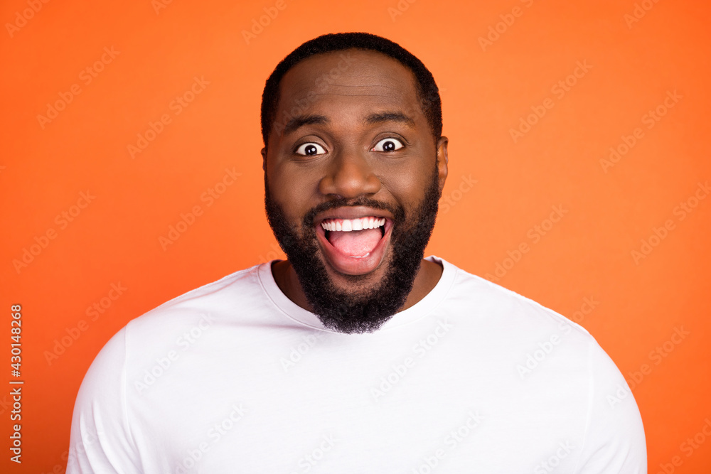 Photo of amazed happy charming dark skin man good mood news isolated on orange color background Photo of amazed happy charming dark skin man good mood news isolated on orange color background