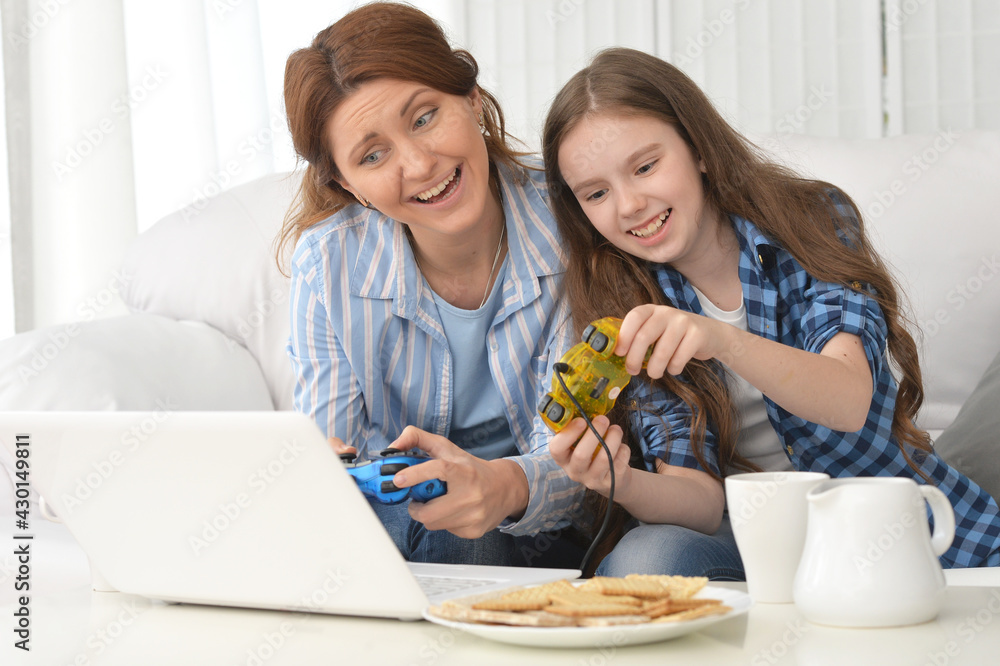 Portrait of smiling mother and daughter using laptop playing video game