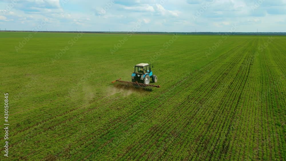 Aerial photography drone shot of tractor pulling disc harrow machine on field, wide shot flying sideways from behind . Concept of work in agricultural farm for making business and having profit from Aerial photography drone shot of tractor pulling disc harrow machine on field, wide shot flying sideways from behind . Concept of work in agricultural farm for making business and having profit from