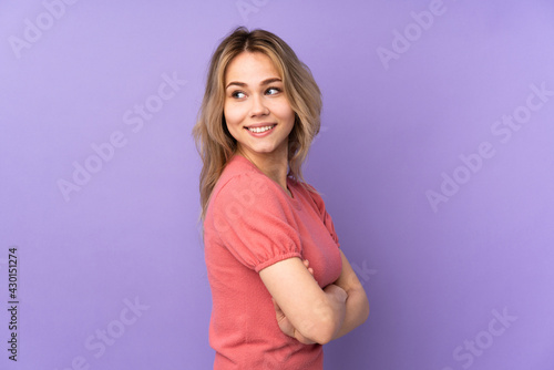 Teenager Russian girl isolated on purple background with arms crossed and happy