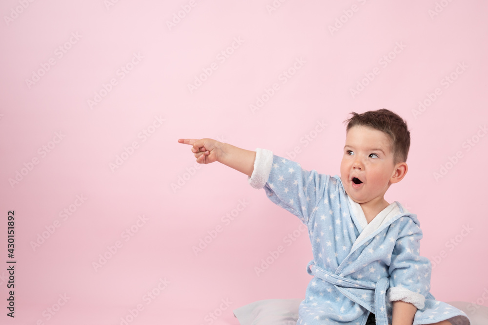 Surprised little boy points with his hand to the side, pink background with empty space. Surprised little boy points with his hand to the side, pink background with empty space.