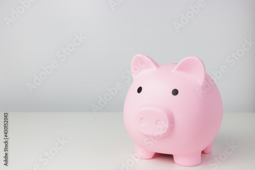 Pink piggy bank stands up on white table isolated on white background with copy space. Money deposit and finance concept.