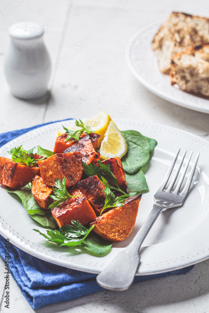 Baked sweet potato salad with spinach on white plate. Baked sweet potato salad with spinach on white plate.