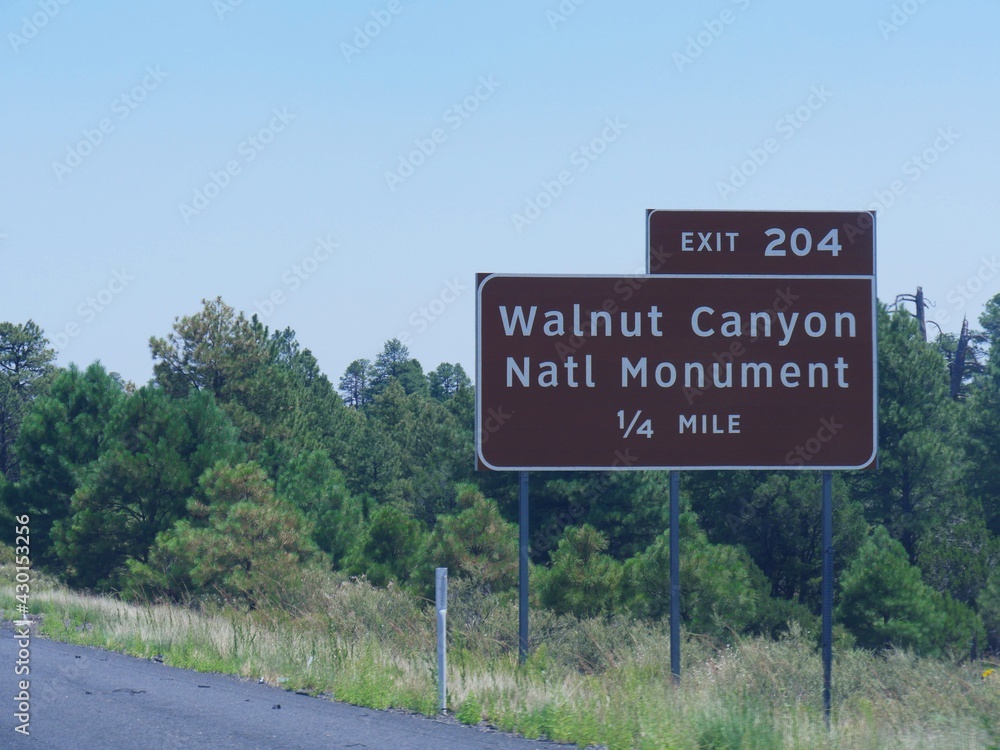 Roadside sign with distance information and exit to the Walnut Canyon National Monument in Arizona.