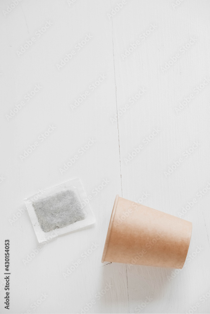 Obraz premium Paper cup and square dry tea bag on a white background. Top view. Copy, empty space for text