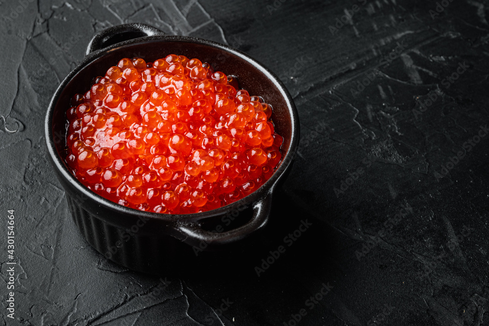 Red salmon caviar in black bowl, on black background  with copy space for text