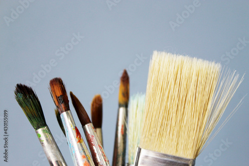 Old and new brushes with dried paint on a gray background. Artistic background