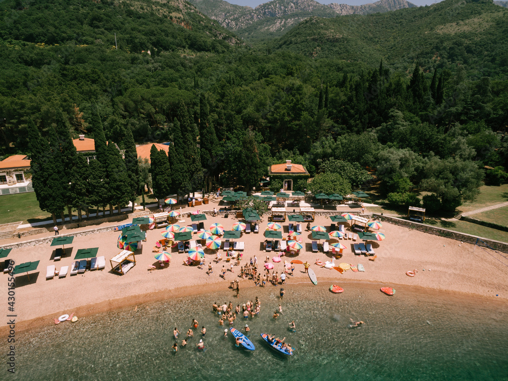 Top view of the royal beach in Przno. Colored sun umbrellas stand on the sand, people swim in the sea and sail in boats