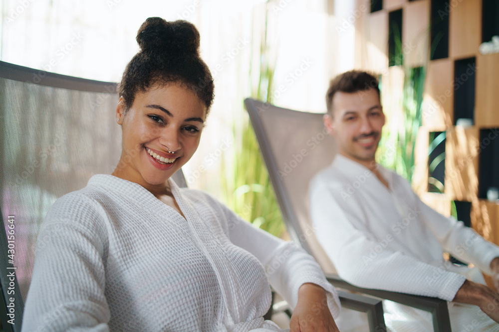 Portrait of young couple sitting and looking at camera in spar resort, relaxing. Portrait of young couple sitting and looking at camera in spar resort, relaxing.