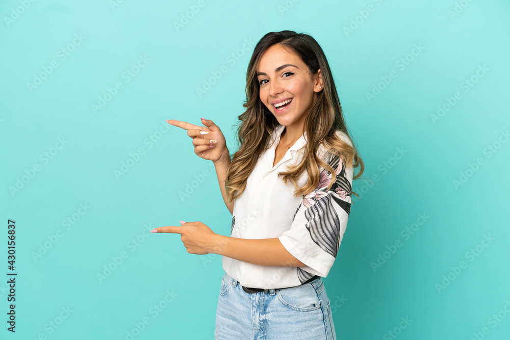Young woman over isolated blue background surprised and pointing side Young woman over isolated blue background surprised and pointing side
