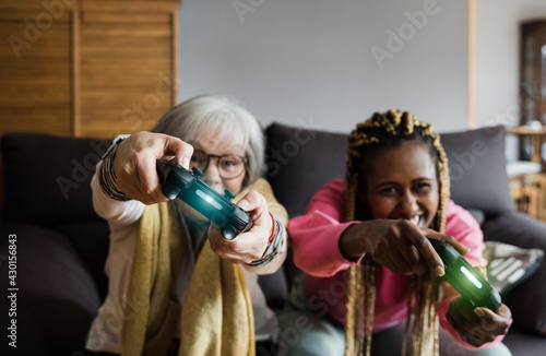 Multi generational senior and young woman playing video games at home - Multiracial people having fun with technology trends - Focus on left woman hands