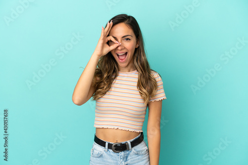 Young woman over isolated blue background showing ok sign with fingers