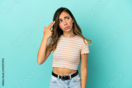 Young woman over isolated blue background with problems making suicide gesture