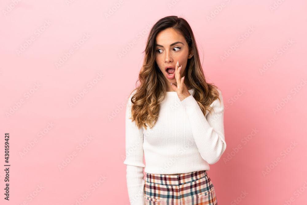 Young woman over isolated background whispering something with surprise gesture while looking to the side Young woman over isolated background whispering something with surprise gesture while looking to the side