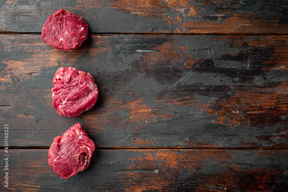 Raw organic grass feed Filet Mignon, on old dark  wooden table background, top view flat lay, with copy space for text
