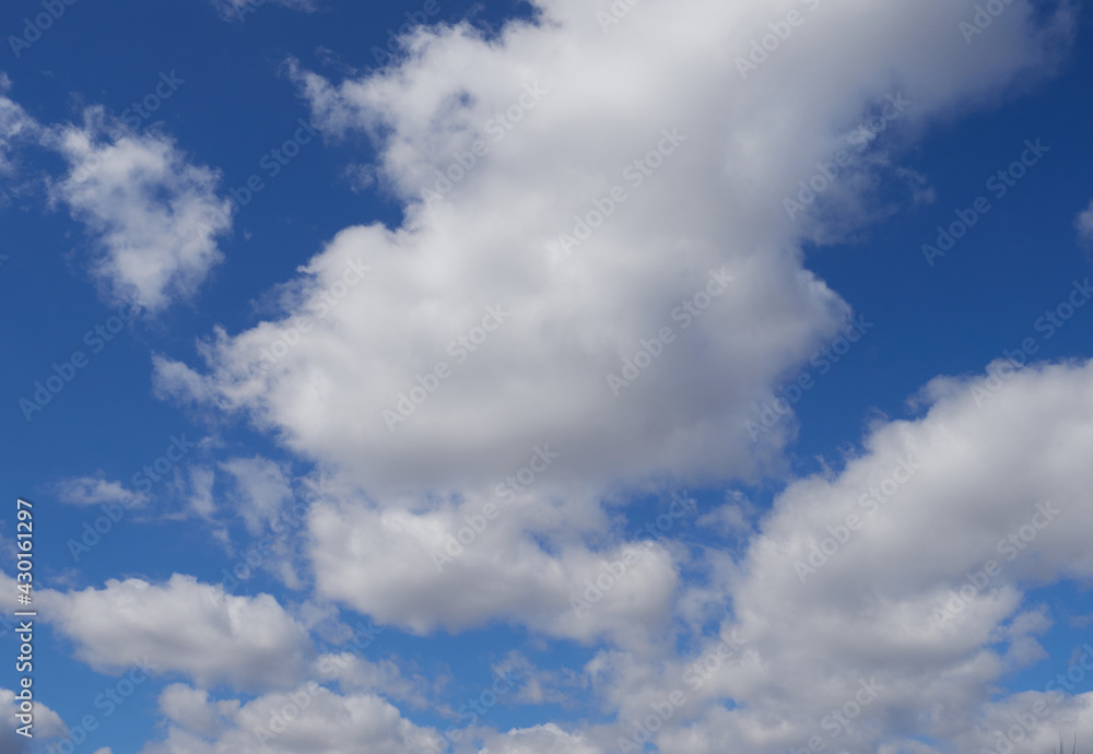 Natural sunny blue sky background with beautiful lush white cumulus clouds and fluffy cirrus clouds Natural sunny blue sky background with beautiful lush white cumulus clouds and fluffy cirrus clouds