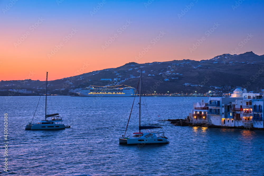 Fototapeta premium Sunset in Mykonos, Greece, with cruise ship and yachts in the harbor