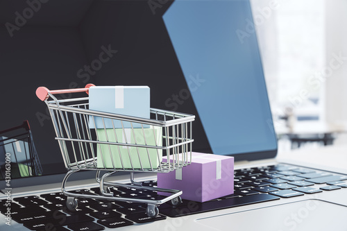 Online supermarket concept with shopping cart and small boxes on laptop keyboard photo