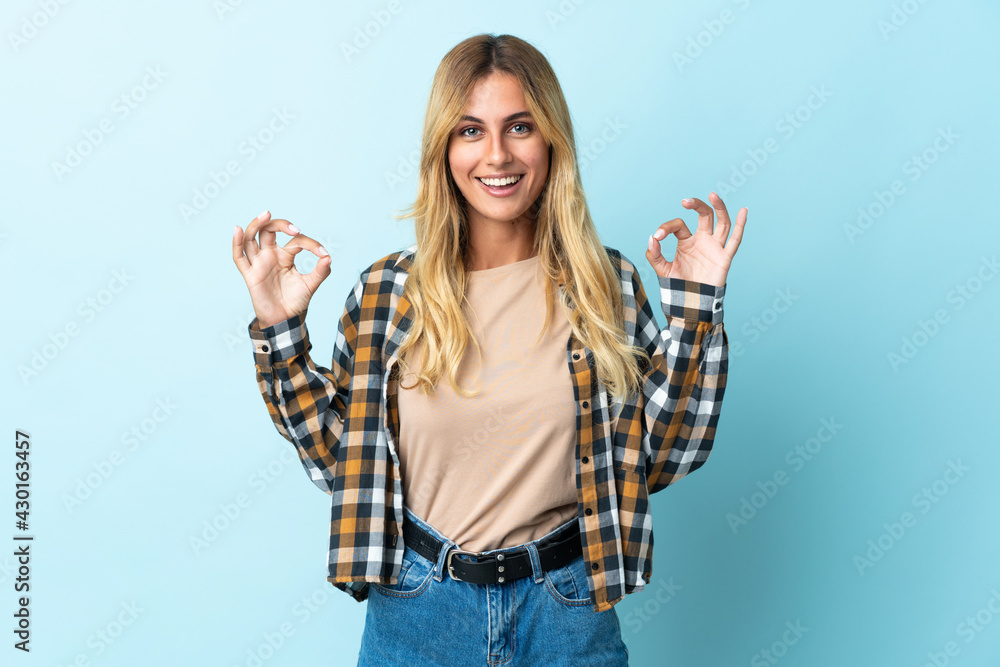 Obraz premium Young blonde Uruguayan isolated on blue background showing ok sign with two hands