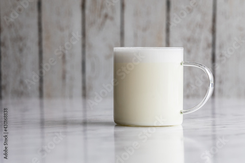 Warm frothy milk in a transparent glass cup
